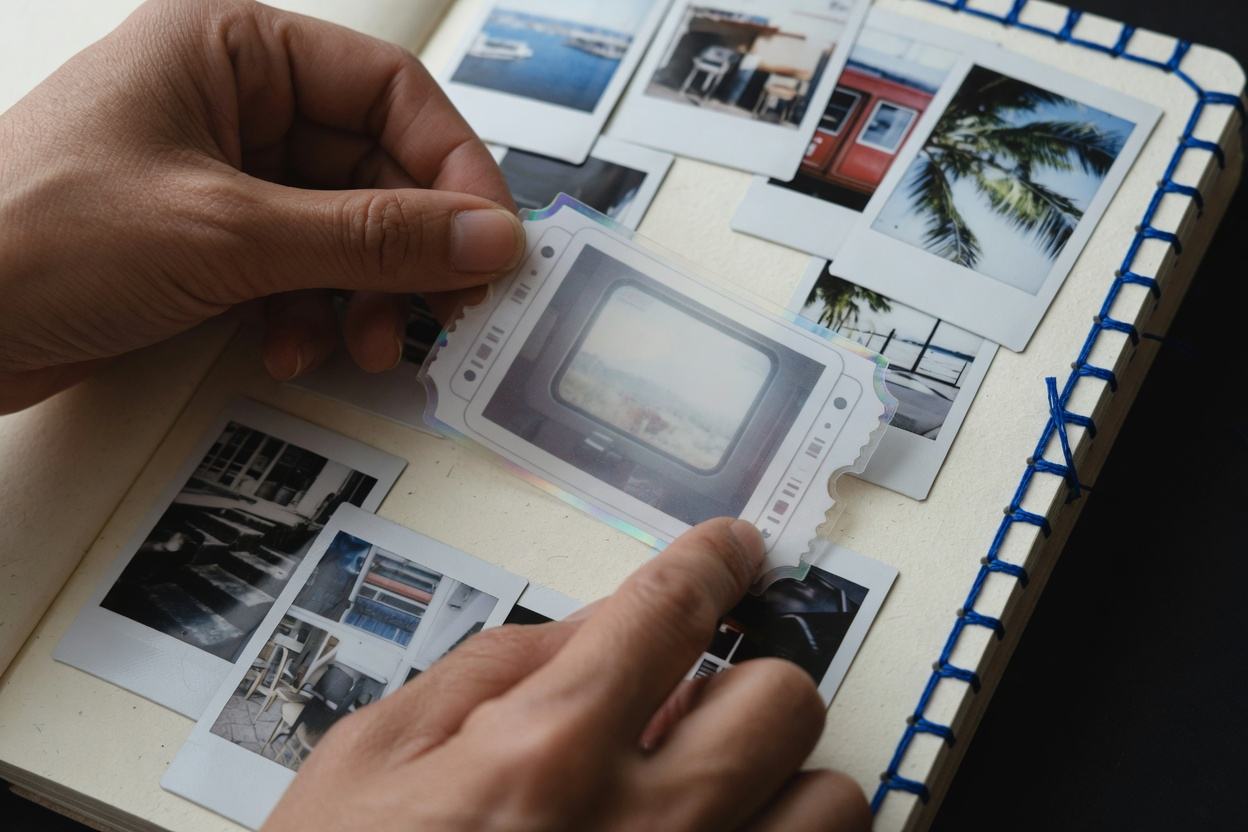 Hands placing a film-ticket sticker into a travel journal.